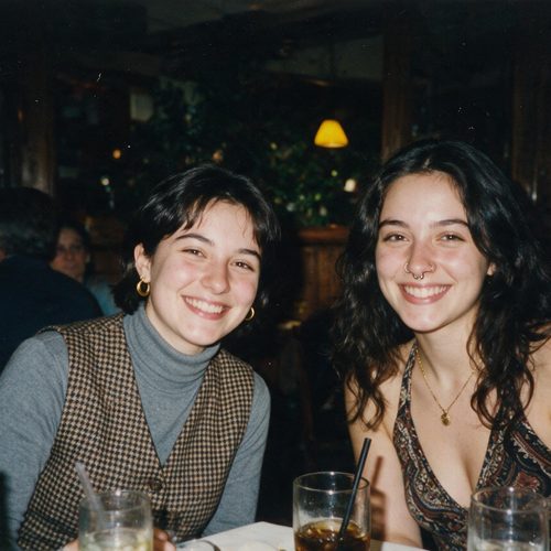 Two friends smiling together at a restaurant table