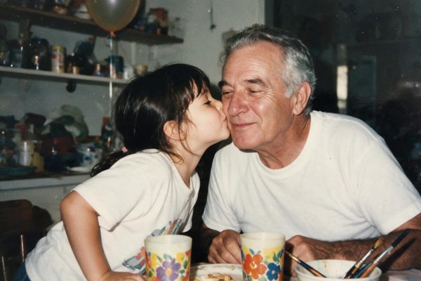 A little girl kissing her grandfather on the cheek at the kitchen table